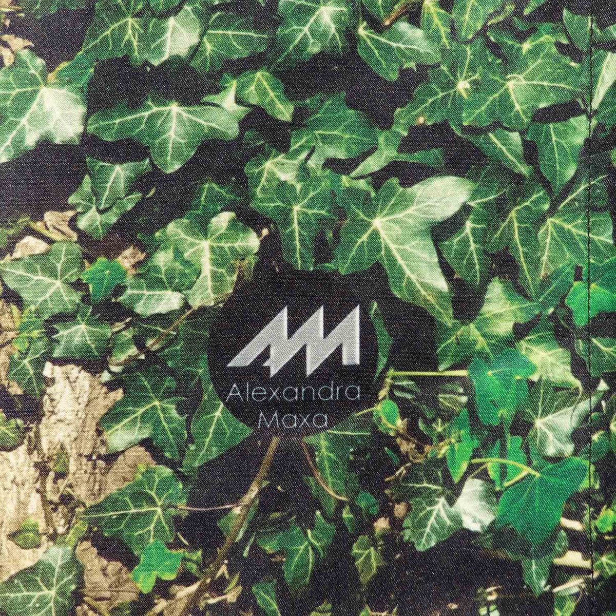 Dirndlschürze "Baumhaus" in Midi von Alexandra Maxa - Detailansicht von dem Digitaldruck einer Eveuranke und dem Logo