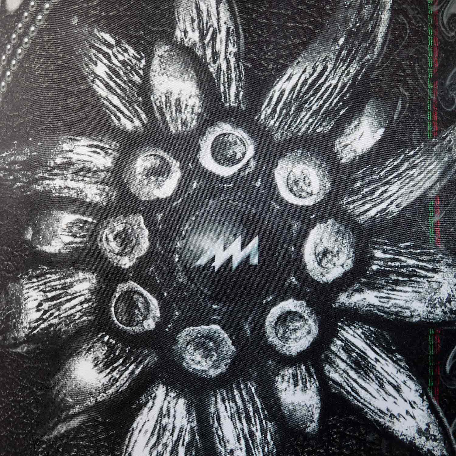 Dirndlschürze "Alpenrock" in Midi von Alexandra Maxa - Detailansicht von einem Edelweiss in Metall-Optik mit Logo